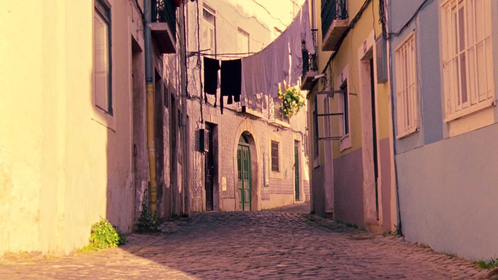 A warm cobbled Alfama alleyway at golden hour